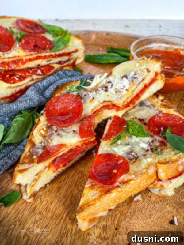 Pepperoni Pizza Grilled Cheese Melt 3 A Pepperoni Pizza Grilled Cheese sandwich cut in half, showcasing layers of pepperoni, melted cheese, and sauce.