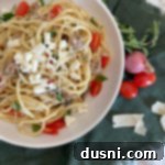 Top view of white plate with pasta, Italian Sausage, and tomatoes