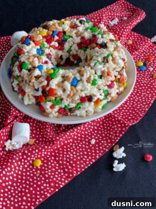 Popcorn Cake on a stand with a slice removed, showing M&M's and peanuts inside.