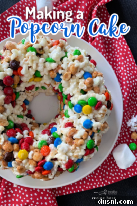 Top-down view of a Popcorn Cake on a pink and white polka dot background, with M&M's scattered.