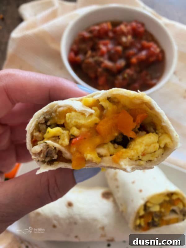 A plate of two breakfast burritos, one cut in half