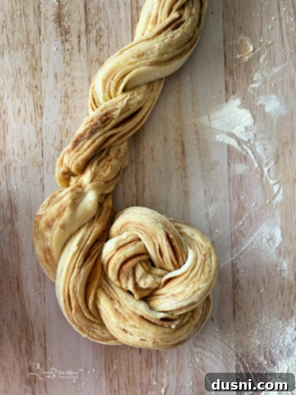 Step-by-step instruction showing two dough strands being twisted together to form the braid for Russian Rose Bread