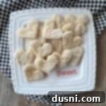 Heart shaped pie crust cookies on a white, square dish.