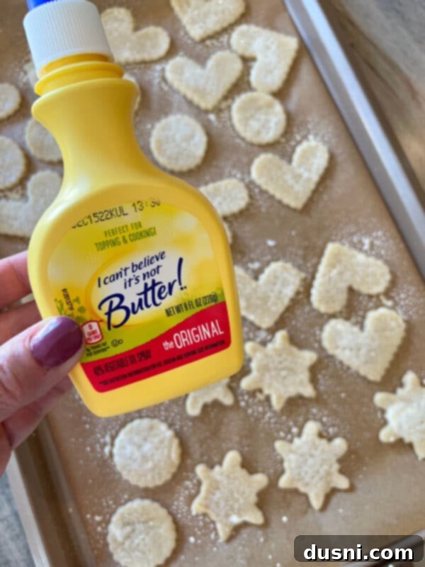 Fork poking holes in uncooked pie crust cookies on a baking sheet