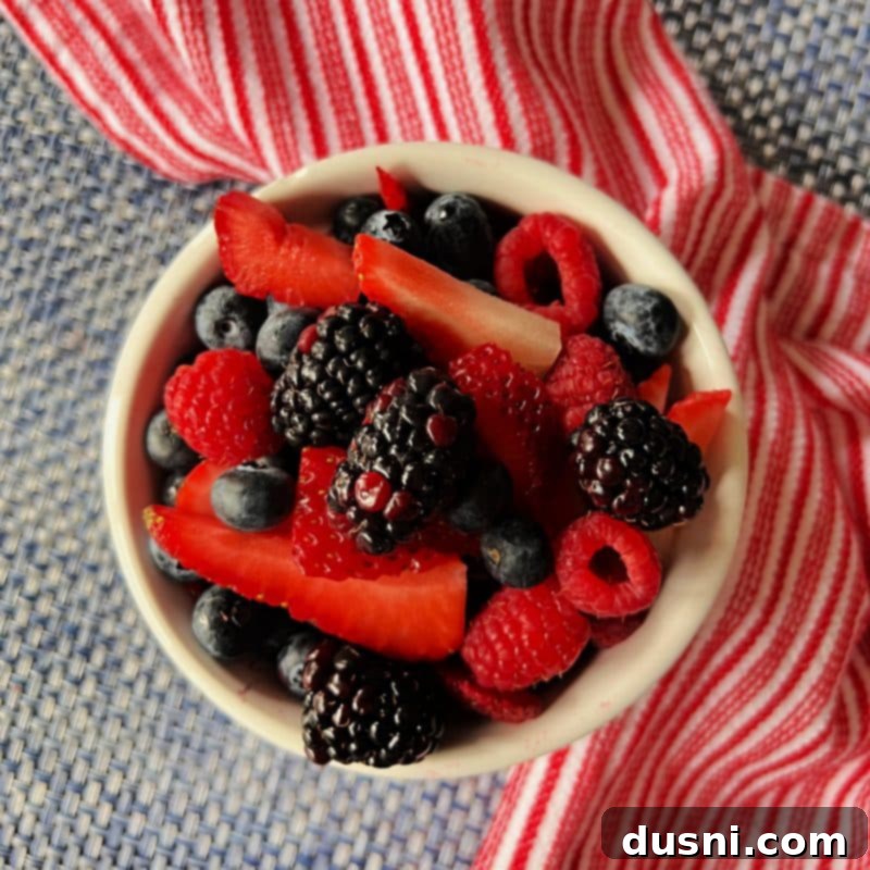 Culinary Anthem Remix 6 Close-up of freshly cut strawberries, blueberries, and raspberries in a bowl, ready for assembly.