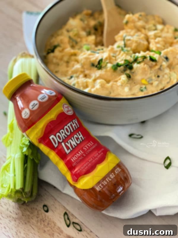A close-up shot of creamy potato salad in a white bowl, garnished with fresh chives, ready to be served.