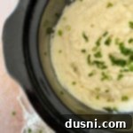 Ultimate Creamy Slow Cooker Mashed Potatoes 23 Top view of mashed potatoes in the Crockpot with chives