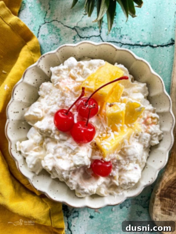 Island Piña Whip 2 Top view of piña colada fluff salad with cherries, showcasing its vibrant and fluffy texture