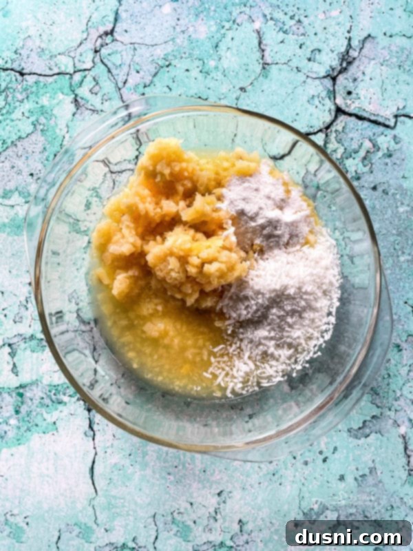 Island Piña Whip 7 Clear bowl containing crushed pineapple, pudding mix, and coconut, ready to be combined