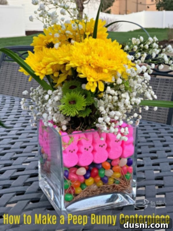 A stunning Easter Peep Centerpiece, showcasing the vibrant combination of marshmallow Peep bunnies, colorful jelly beans, and fresh spring flowers in a square glass vase, perfect for holiday decor.