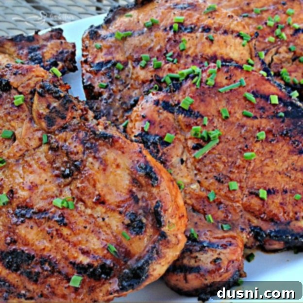 Platter of Apple Moonshine Glazed Pork Chops, garnished with fresh herbs