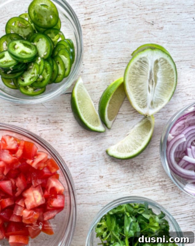 A vibrant selection of fresh garnishes including chopped tomatoes, green cilantro, sliced jalapeños, lime wedges, and red onions, perfect for topping cilantro lime pork.
