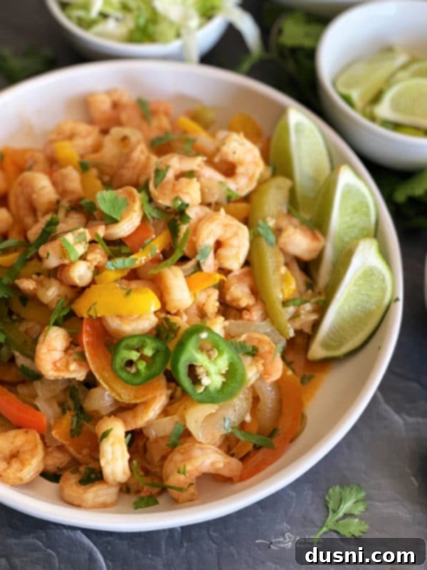 Sheet Pan Cilantro Lime Shrimp Fajitas with bell peppers and onions, topped with fresh cilantro and lime wedges.