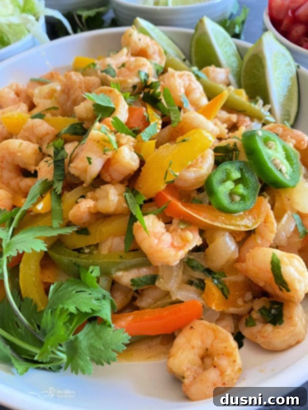 A bowl of cooked sheet pan shrimp fajitas, ready to be eaten with a fork.