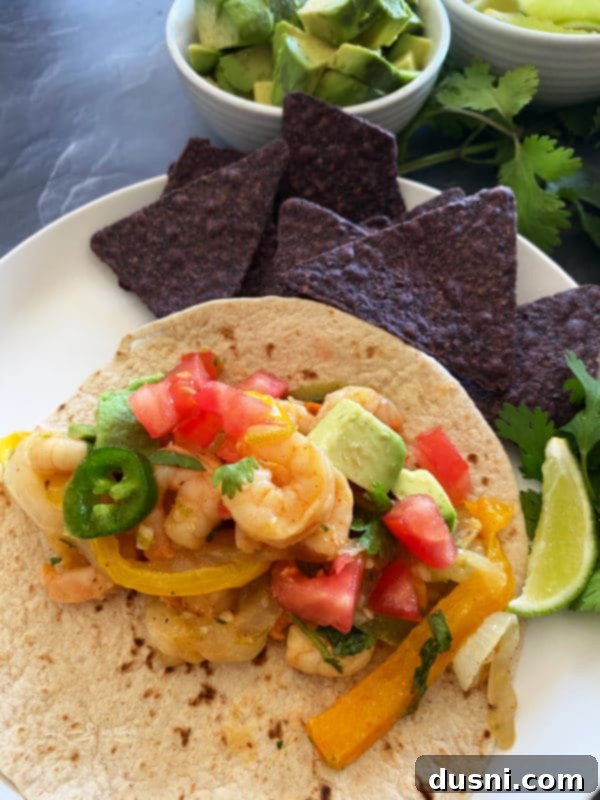 Various serving suggestions for sheet pan shrimp fajitas including tortillas, avocado, salsa, and cheese.