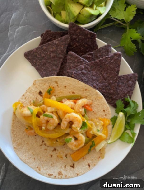 Close up of cooked cilantro lime shrimp fajitas in a pan with bell peppers and onions.