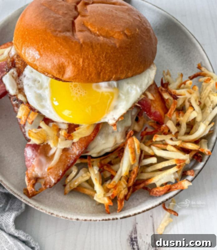 A large, juicy Hangover Burger with all the fixings, including a fried egg, bacon, and hash browns, served on a bun.