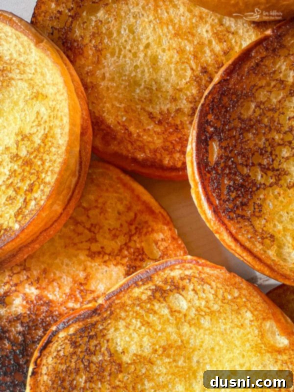 Butter being spread on the inside of burger buns before toasting.