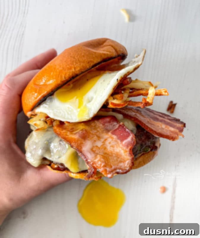 A close-up of a Hangover Burger revealing the layers of fried egg, bacon, and cheese.