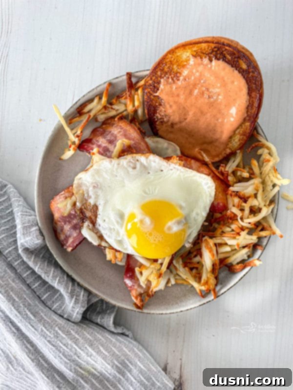 Another perspective of the Hangover Burger, showing the thick patty, egg, and hash browns.