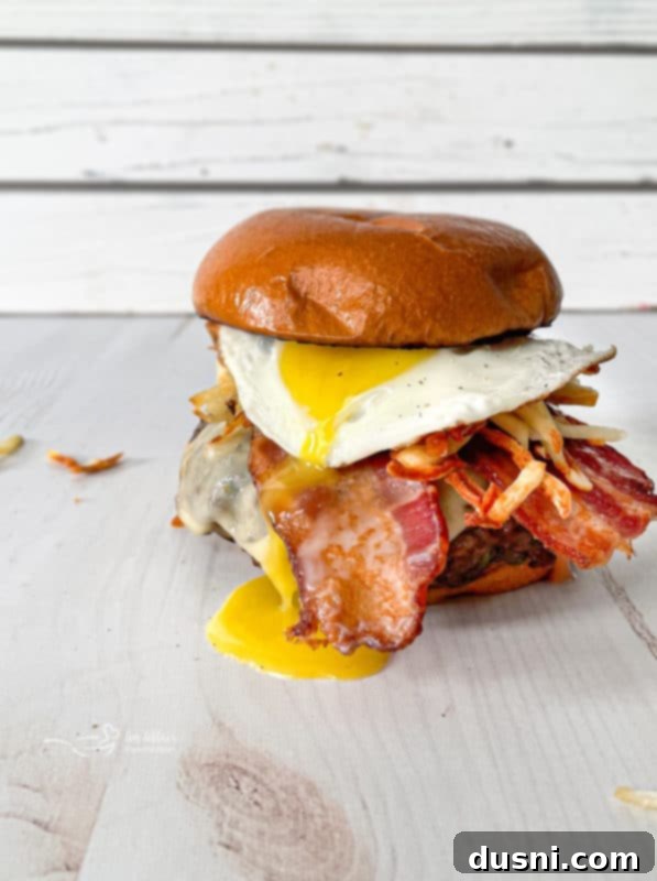 The Hangover Burger served on a plate with crispy hash browns and a runny egg yolk.