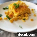 Close-up of baked corn pie casserole on a white plate, garnished with fresh parsley