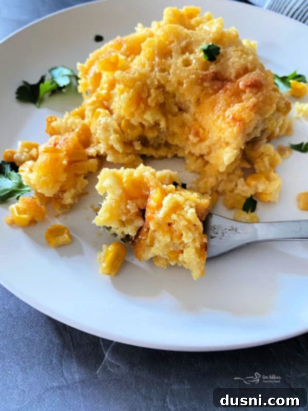 Close-up front view of a portion of creamy corn pie pudding with a fork, showing its tender texture