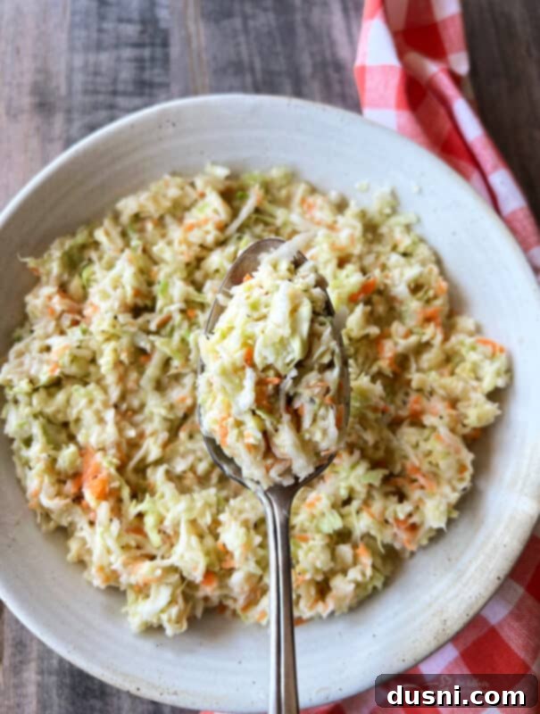 Serving of KFC Copycat Coleslaw in a white bowl with a spoon