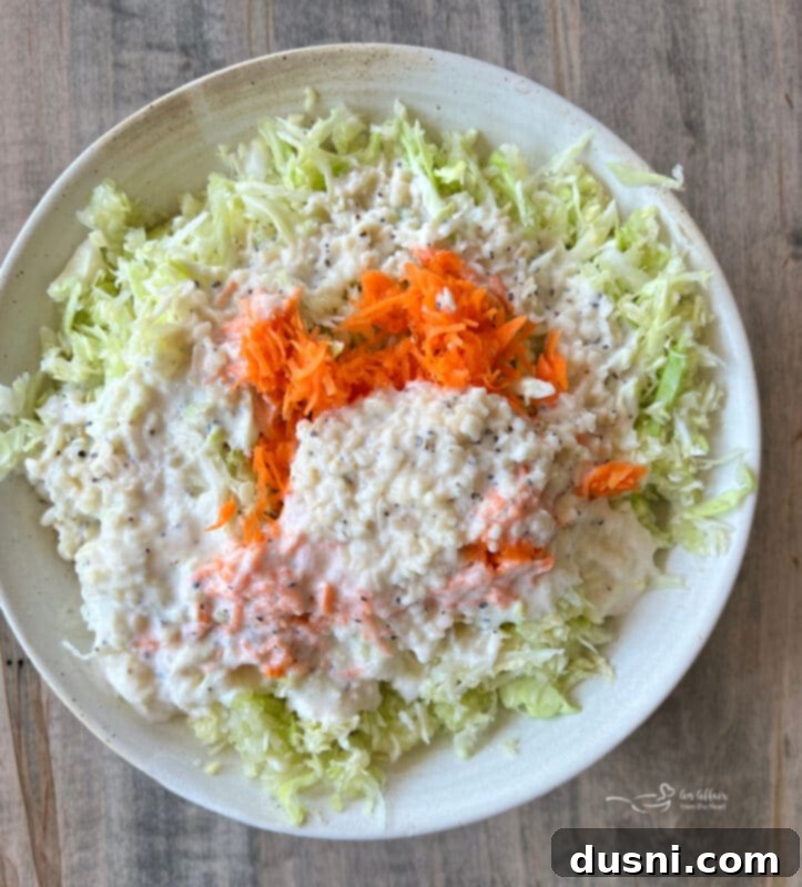 Pouring dressing over shredded cabbage and carrots for KFC Copycat Coleslaw