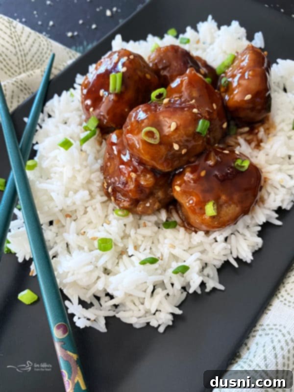 Sticky Asian Meatballs served over rice with a sprinkle of green onions