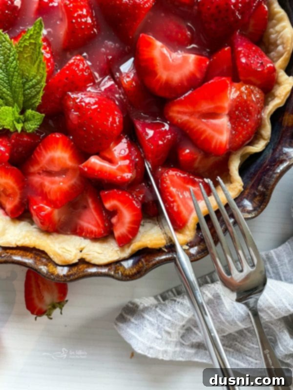 Top view of a fresh strawberry pie with a knife and fork, ready to be served