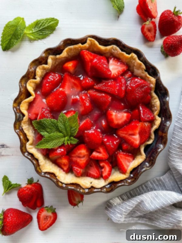 Top view of a fresh strawberry pie with a sprig of mint