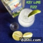 Zingy Key Lime Sparkle 2 Overhead view of a sparkling Key Lime Fizz, garnished with fresh lime, next to Key Lime Rum and a shot glass.