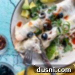 Two enchiladas on plate with fork and knife