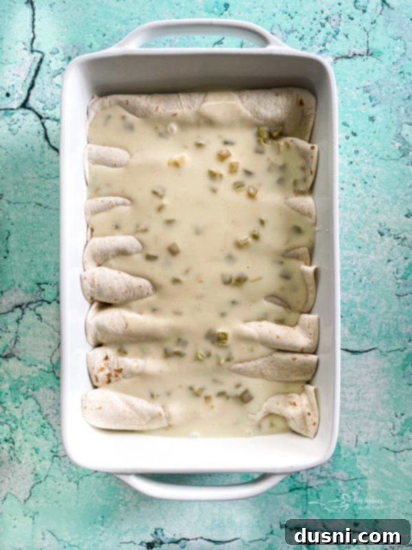 Enchiladas in white dish covered in cheese sauce