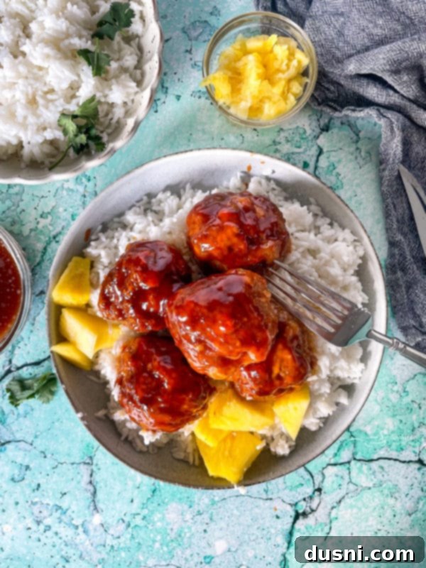 Crockpot Luau Chicken Sandwiches 13 Top view of Hawaiian ham balls on plate with rice and pineapples