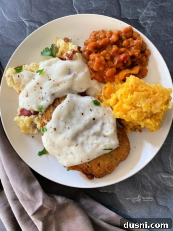 Plate of chicken patties and mashed potatoes with gravy, beans, and corn pie pudding