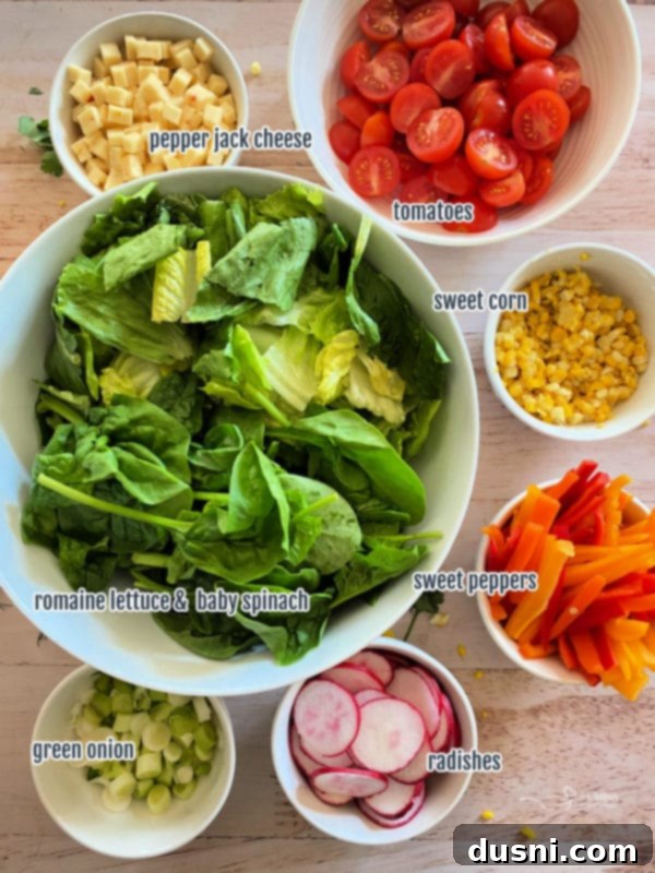 top view of greens, cheese, tomatoes, corn, peppers, radishes, green onion