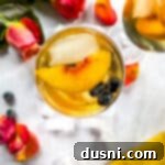 Overhead of rose sangria topped with slices of peach and blueberries.