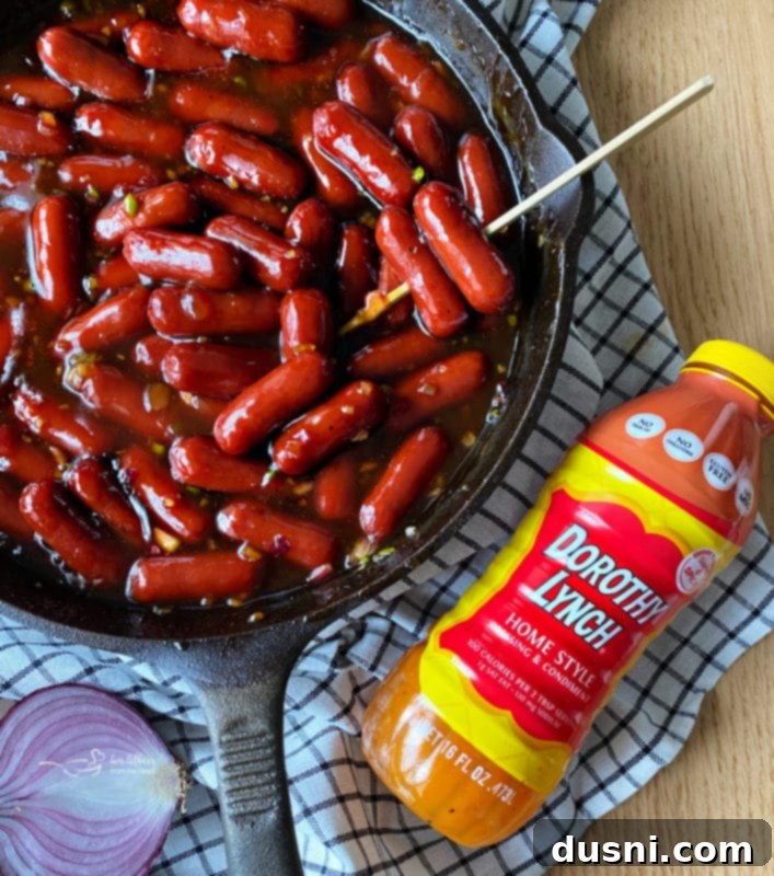 Dorothy's BBQ Little Smokies simmering in a skillet on a stovetop.