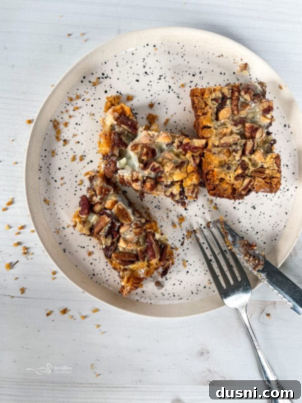 Seven Layer Magic Bars 3 seven layer cookies on speckled plate with knife and fork