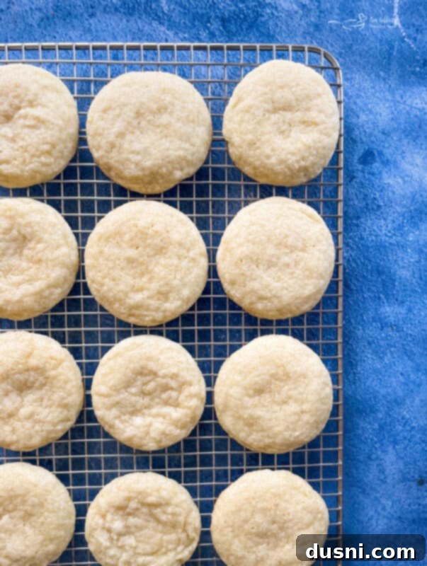 Sunshine Lemon Chewies 10 Freshly baked lemon cookies cooling on a parchment-lined baking sheet.