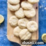 Sunshine Lemon Chewies 20 Glazed lemon cookies stacked on a wooden cutting board.
