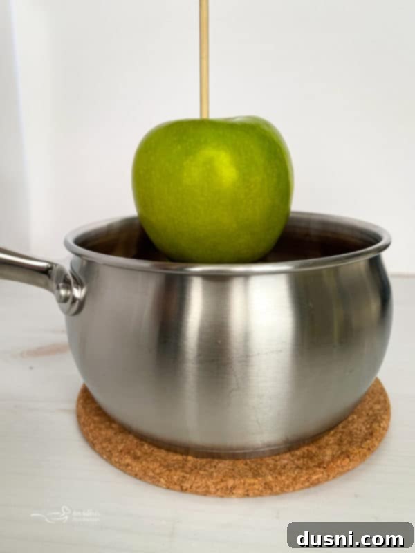 Crafting Golden Caramel Apple Treats 9 Dipping a Granny Smith apple into warm homemade caramel
