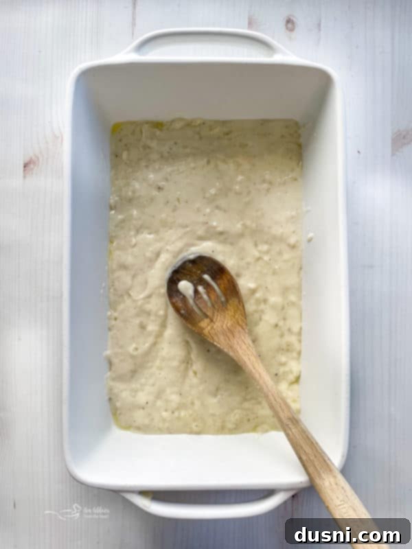 spreading sauce in bottom layer of baking dish with spoon 
