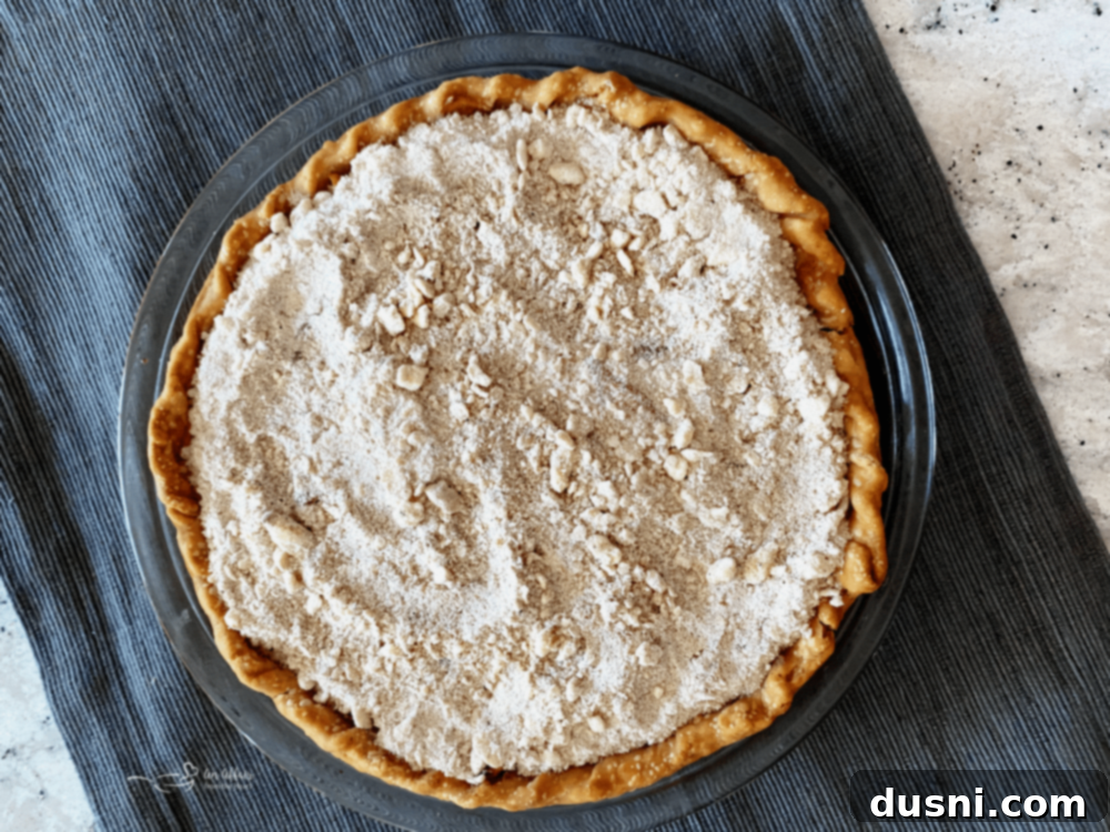 Golden Crumb Spiced Peach Pie 12 Crumb topping being sprinkled over the partially baked peach pie.