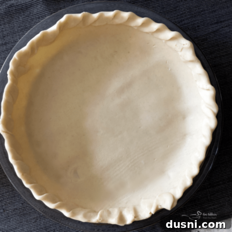 Golden Crumb Spiced Peach Pie 5 Pie crust being pressed into a pie plate.