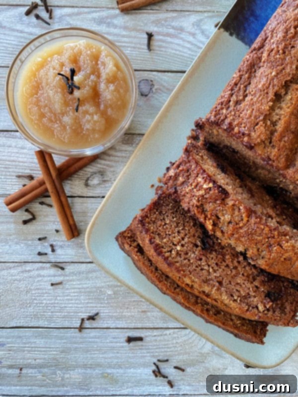 Chocolate Chip Spice Bread one loaf of applesauce bread on plate with bowl of applesauce and cinnamon sticks