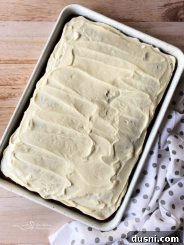 Easy Carrot Cake Bars with Cream Cheese Frosting A top-down view of a pan full of freshly baked carrot cake bars, beautifully topped with a smooth, generous layer of cream cheese frosting.