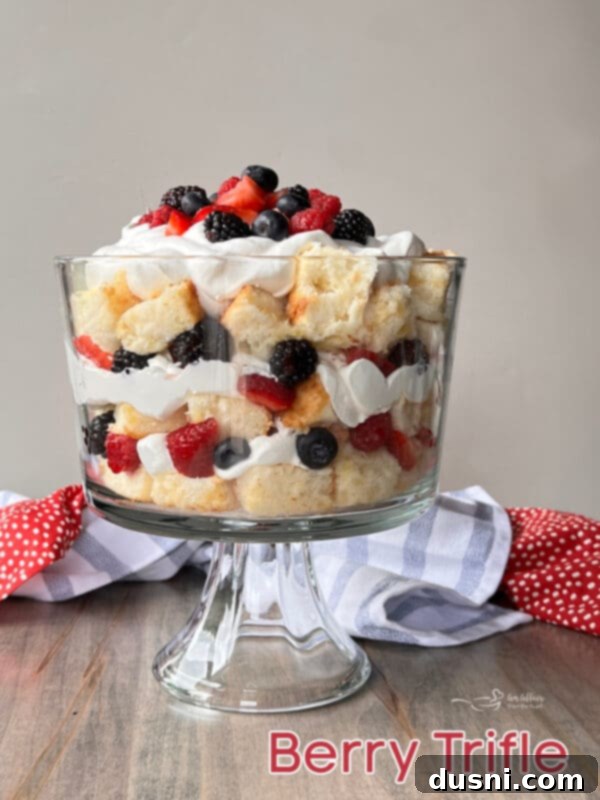 A Berry Trifle in a glass serving bowl, with a spoon ready to scoop, highlighting its delicious layers.